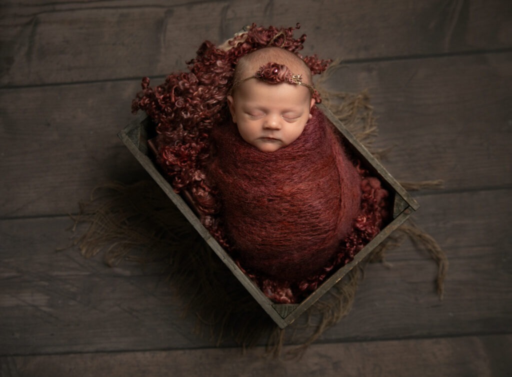 baby wrapped in burgundy